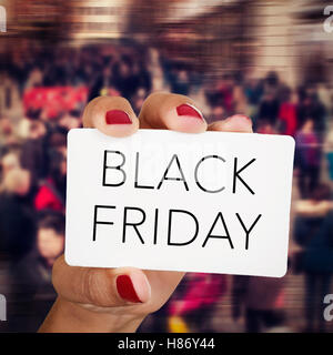 Libre de la main d'une jeune femme de race blanche avec ses ongles peints en rouge montrant une pancarte avec le texte vendredi noir, en fro Banque D'Images