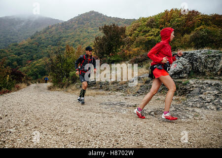 Jeune homme et femme athlètes coureurs courir sur un sentier de montagne au cours de la Crimée marathon de montagne Banque D'Images