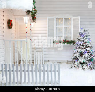 Extérieur d'hiver d'une maison de campagne avec des décorations de Noël dans le style américain. Cour intérieure couverte de neige avec un porche, un arbre Banque D'Images