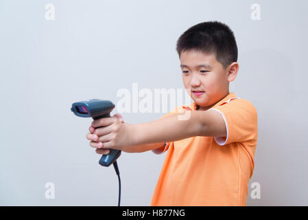 Asian boy but une fausse arme réalisée avec lecteur de codes à barres, studio shot, sur fond de mur gris avec soft shadow Banque D'Images