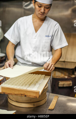 Un petit producteur Artisanal bonbons appelé wagashis. un chef couvrant un bac de petits bonbons moulés pour le séchage. Banque D'Images