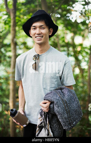 Portrait of a smiling man wearing a hat, debout dans une forêt. Banque D'Images