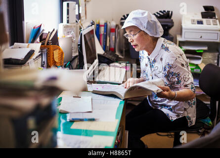 Une femme mature à un bureau de l'office d'une unité de restauration rapide et de nouilles en usine de production. Banque D'Images