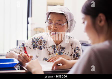 Une femme mature à un bureau de l'office d'une unité de restauration rapide et de nouilles en usine de production. Banque D'Images