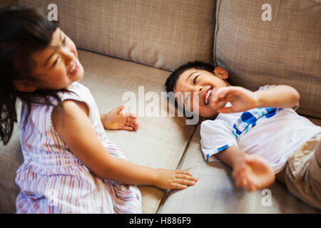 Maison de famille. Deux enfants jouant sur le sol, à rire. Banque D'Images