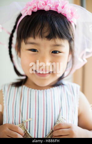 Maison de famille. Une jeune fille en robe rose, dans un bandeau et voile net. Banque D'Images