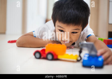 Maison de famille. Un garçon jouant avec des voitures sur le plancher. Banque D'Images