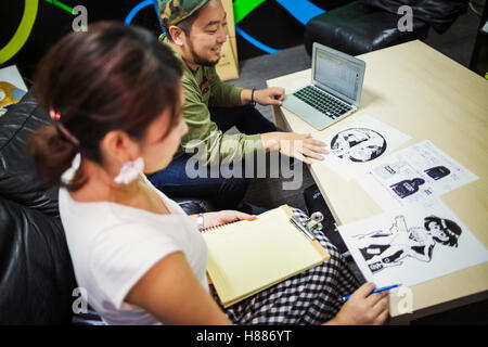 Design Studio. Deux collègues, l'homme et de la femme, assis discutant dessins imprimés. Banque D'Images