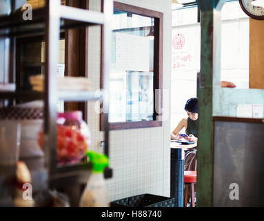 La boutique de nouilles ramen. Une femme assise dans un café, vue à travers une porte. Banque D'Images