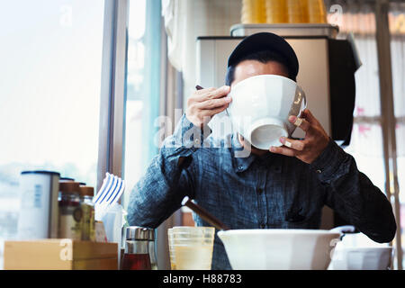 Un café de nouilles ramen dans une ville. Un homme assis manger nouilles ramen à partir d'un grand bol de bouillon. Banque D'Images