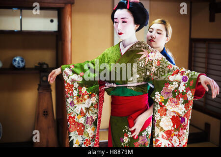 Une femme d'être habillés en style geisha, vêtu d'un kimono et obi, avec une coiffure élaborée et floral pinces à cheveux Banque D'Images