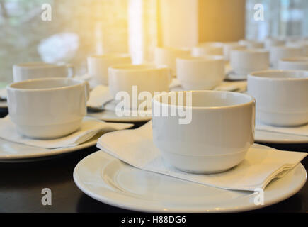 De nombreuses tasses à café blanches attendent servant avec effet de lumière solaire, vintage style ; focus sélectif à l'avant-plan flou et b Banque D'Images