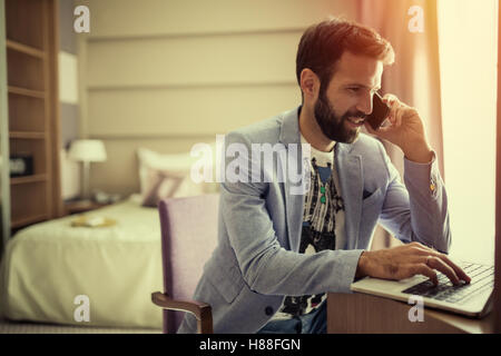 Homme d'affaires occupé le travail à domicile sur ordinateur portable et téléphone Banque D'Images