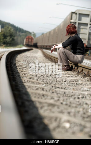 Jeune femme assise sur une voie de chemin de fer Banque D'Images