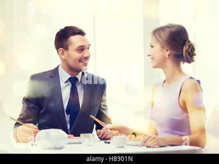 Smiling couple manger des sushis au restaurant Banque D'Images