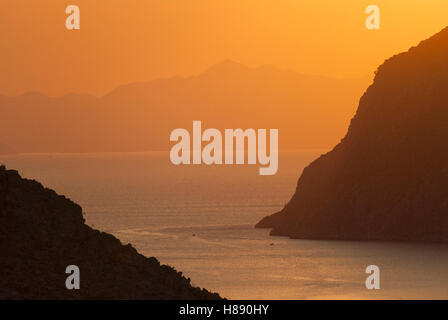 La recherche à travers la baie de Pedi sur l'île de Symi. avec les collines de la Turquie derrière, à l'aube. Banque D'Images