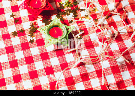 Bougie sur nappes à carreaux rouges et Garland. Banque D'Images