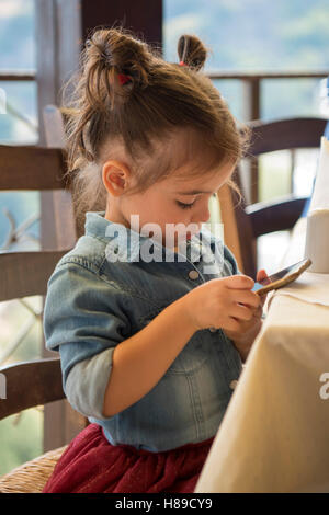 Spanien, Kreta, Rodia westlich von Iraklio, Restaurant Rodi, fille jouant sur un smartphone Banque D'Images