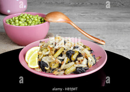 Pommes de terre sautées aux champignons et oignons. Petits pois dans un bol une cuillère. Banque D'Images