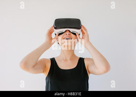 Coup de jeune femme en utilisant le casque de réalité virtuelle et souriant contre fond gris. Happy female mannequin portant des lunettes VR Banque D'Images
