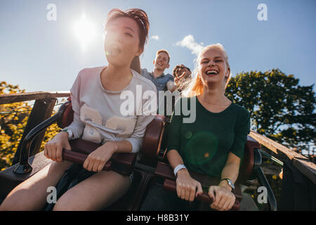 Jeunes amis enthousiastes sur roller coaster ride. Les jeunes s'amuser au parc d'amusement. Banque D'Images