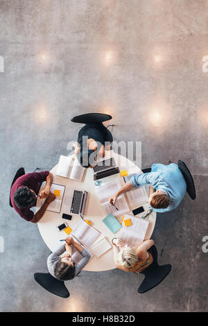 Groupe d'étudiants d'étudier ensemble. High angle shot de jeunes gens assis à la table et l'étude avec des livres et d'ordinateurs portables co Banque D'Images