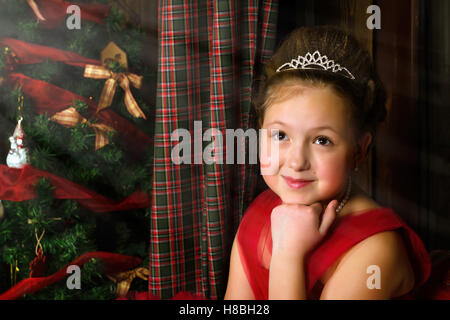 La princesse d'hiver - pensive cute little girl in red dress se félicite de nouvel an et de Noël à l'intérieur de charme Banque D'Images