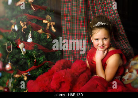 La princesse d'hiver - cute little girl in red dress se félicite de nouvel an et de Noël à l'intérieur de charme Banque D'Images