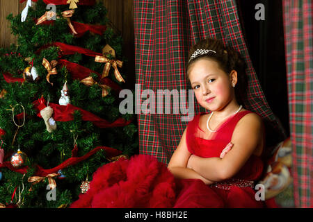 La princesse d'hiver - cute little girl in red dress se félicite de nouvel an et de Noël à l'intérieur de charme Banque D'Images