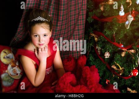 La princesse d'hiver - cute little girl in red dress se félicite de nouvel an et de Noël à l'intérieur de charme Banque D'Images