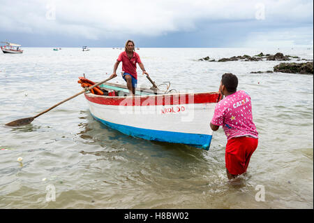 SALVADOR, BRÉSIL - février 23, 2016 : les pêcheurs brésiliens manœuvrer un bateau traditionnel le long sur le bord d'un village de pêcheurs. Banque D'Images