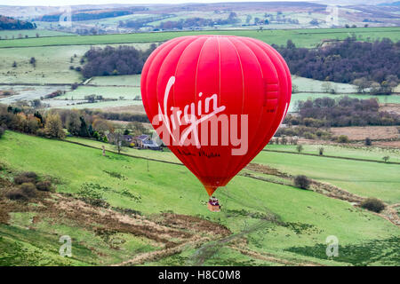 Une Vierge hot air balloon décollant d'un champ dans la vallée supérieure de Dove, Peak District National Park Banque D'Images