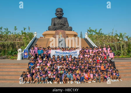 Les enfants de l'école thaïlandaise ayant une photo de groupe devant la sculpture emblématique de moine bouddhiste vénéré Luang Pu Thuat à Wat Huay M Banque D'Images