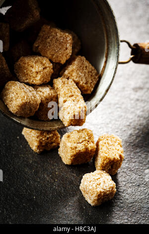 Cubes de sucre organique brun gros plan sur fond sombre, selective focus Banque D'Images