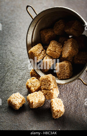 Cubes de sucre organique brun gros plan sur fond sombre, selective focus Banque D'Images