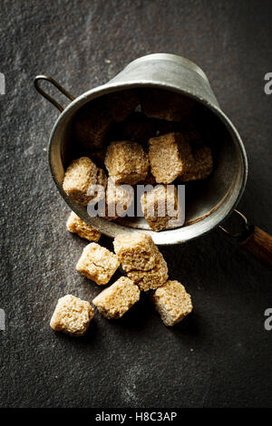 Cubes de sucre organique brun gros plan sur fond sombre, selective focus Banque D'Images