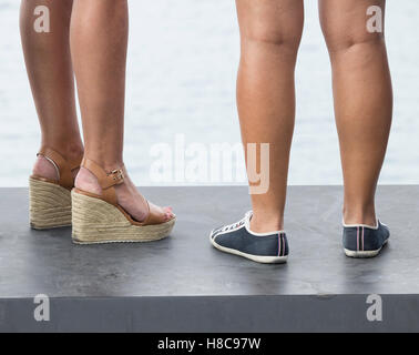 Portrait de femme portant deux différents types de chaussures : Talons hauts et de télévision. Banque D'Images