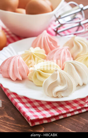 Délicieux cookies meringue couleur frais servis sur plaque blanche avec les oeufs et mixer en arrière-plan Banque D'Images