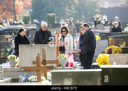 Les gens priant devant des tombes décorées avec des arrangements de fleurs et lampions sur la Toussaint dans Zagreb, Croatie. Banque D'Images