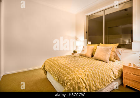 Grand lit de couleur jaune avec des motifs de couleur blanche comprenait, il y a 4 oreillers en blanc et jaune. Deux armoires en bois Banque D'Images