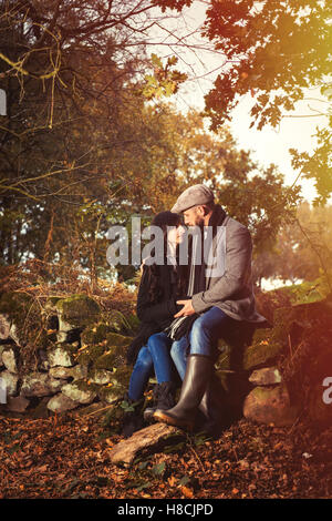 Les jeunes 30 ans couple réglage avec des feuilles d'automne en plein air à la campagne Banque D'Images