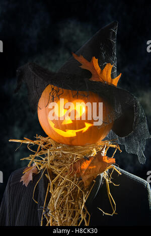 Tête de citrouille portant un chapeau de sorcière avec de la paille et les araignées pour Halloween Banque D'Images