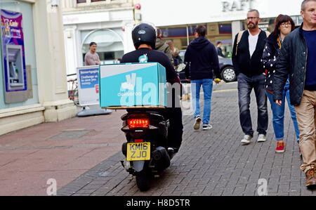 Un Deliveroo rider livraison sur un scooter rides entre les piétons à Brighton, UK Banque D'Images