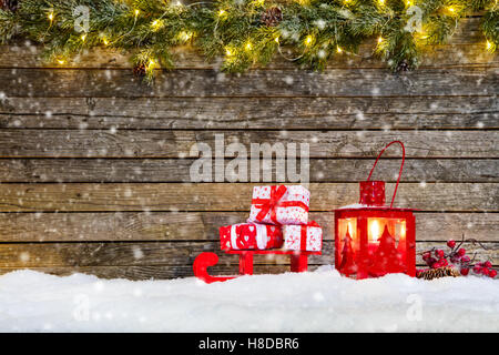 Noël arrière-plan avec des tas de cadeaux mis sur traîneau dans la neige. Décoration sur le dessus des branches de sapin Banque D'Images