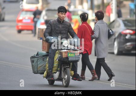 Qingdao, Qingdao, Chine. Nov 11, 2016. Qingdao, Chine-Novembre 11 2016 : (usage éditorial uniquement. La CHINE) Un livreur équitation vélo électrique chargé avec des paquets à Qingdao, province de Shandong en Chine de l'Est, Novembre 11th, 2016. Similaire à vendredi noir et le Cyber lundi aux États-Unis, Chine's Double 11 Shopping Festival est le plus grand centre commercial en ligne jour qui tombe le 11 novembre chaque année. Les statistiques montrent que le Hangzhou-basé de Alibaba a fallu qu'une heure pour atteindre le volume des ventes de 36,2 milliards de yuan le 11 novembre 2016. © SIPA Asie/ZUMA/Alamy Fil Live News Banque D'Images