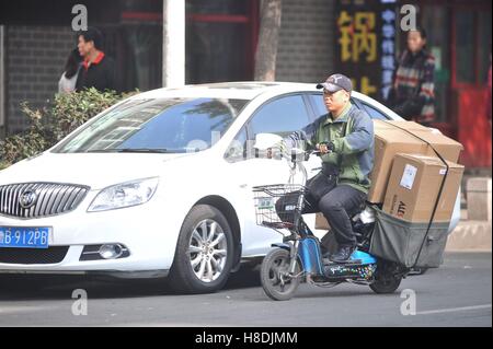 Qingdao, Qingdao, Chine. Nov 11, 2016. Qingdao, Chine-Novembre 11 2016 : (usage éditorial uniquement. La CHINE) Un livreur équitation vélo électrique chargé avec des paquets à Qingdao, province de Shandong en Chine de l'Est, Novembre 11th, 2016. Similaire à vendredi noir et le Cyber lundi aux États-Unis, Chine's Double 11 Shopping Festival est le plus grand centre commercial en ligne jour qui tombe le 11 novembre chaque année. Les statistiques montrent que le Hangzhou-basé de Alibaba a fallu qu'une heure pour atteindre le volume des ventes de 36,2 milliards de yuan le 11 novembre 2016. © SIPA Asie/ZUMA/Alamy Fil Live News Banque D'Images