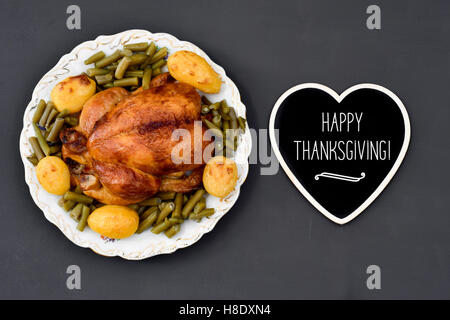 Capture d'un grand angle d'un dindon rôti sur un plateau ronde en céramique et une pancarte en forme de coeur avec le texte joyeux thanksgiving written Banque D'Images