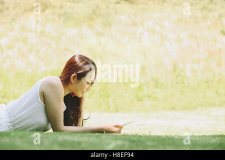 Portrait de jeune japonaise portant sur l'herbe avec tablet Banque D'Images