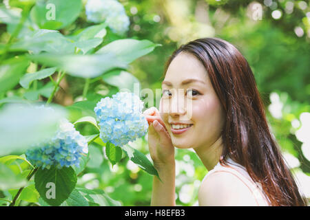 Jeune japonaise avec des fleurs d'hortensias dans un parc de la ville Banque D'Images