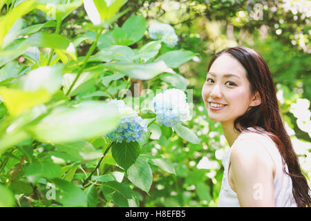 Jeune japonaise avec des fleurs d'hortensias dans un parc de la ville Banque D'Images